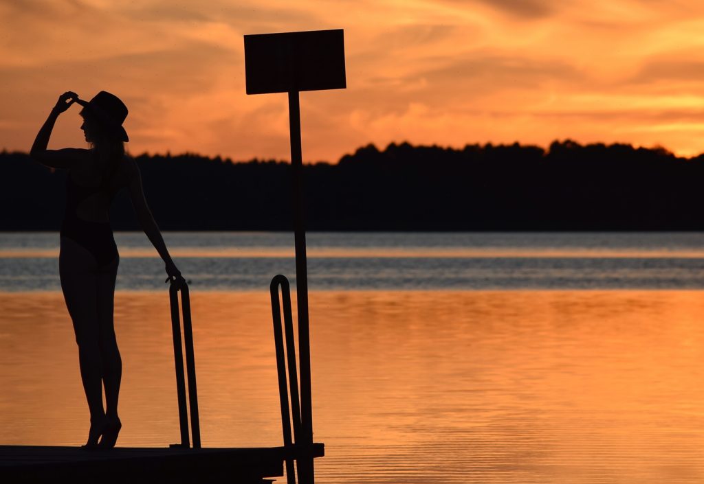 modelka w kapeluszu nad jeziorem podczas zachodu słońca
