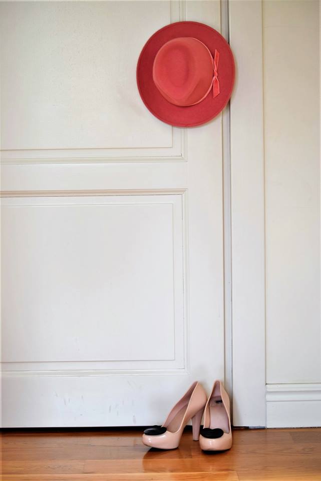 różowy kapelusz wiszący na drzwiach i szpilki na podłodze