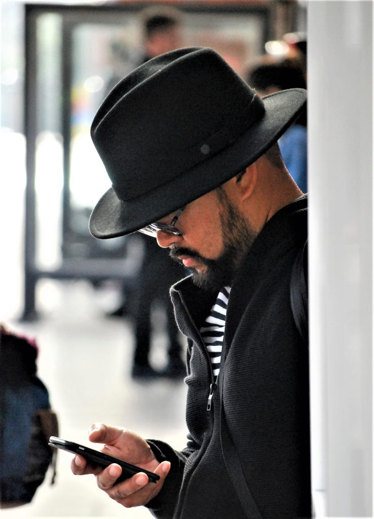 mężczyzna w czarnym kapeluszu przegląda telefon